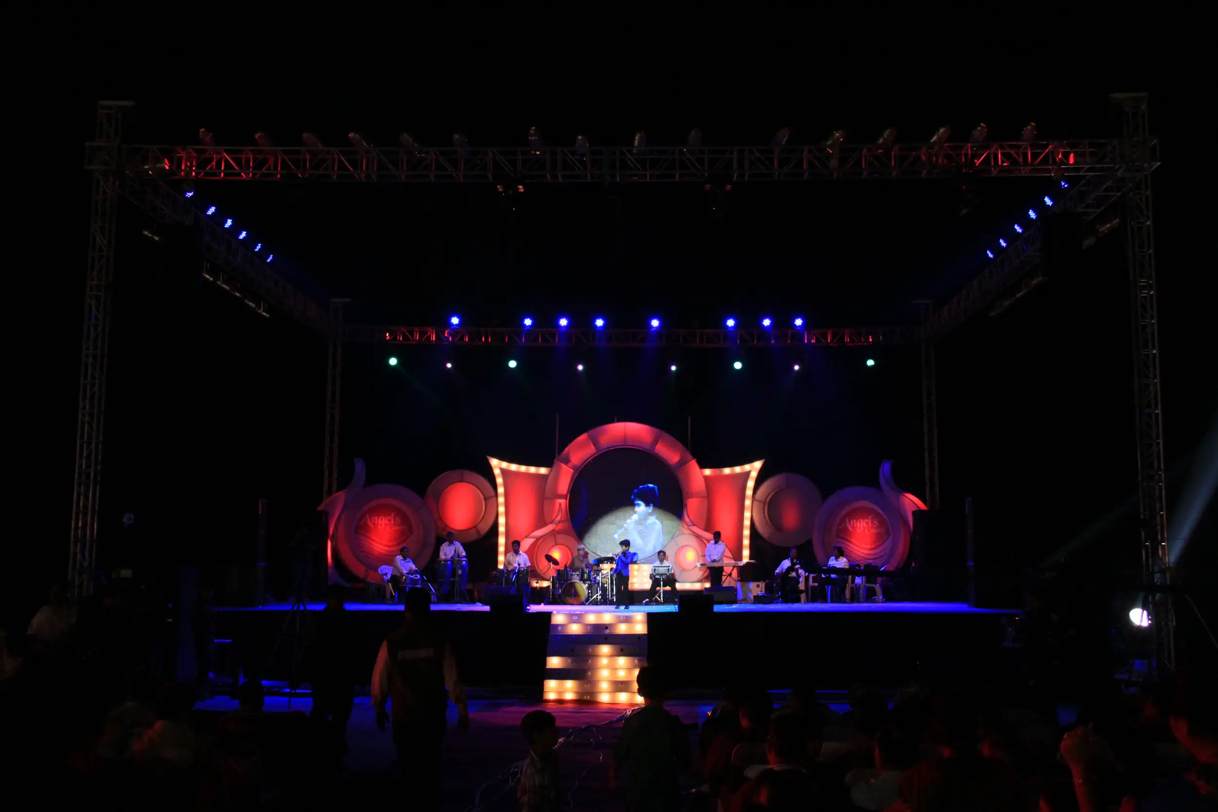 Man and woman speaking on stage at night with blue lighting